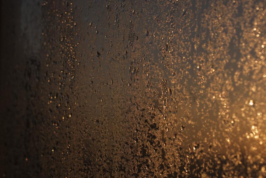 Raindrops on glass against the background of the sun. Abstract background