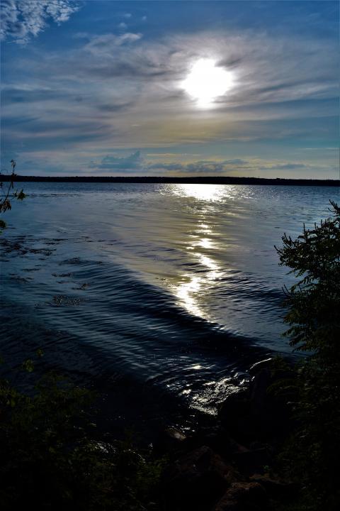 The sun breaks through the clouds over the lake