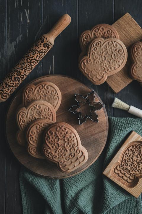 wooden cutting board topped with cookies next to a cookie cutter